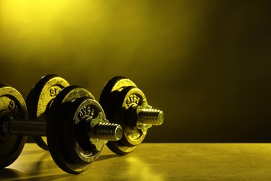 Two barbells on table in color lights. Space for text