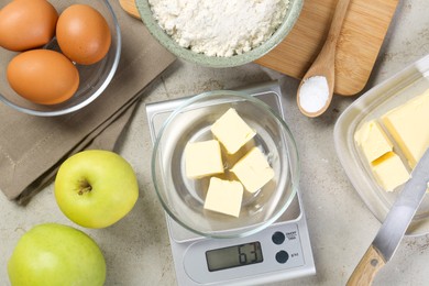 Kitchen scale with bowl of butter and other products on grey table, flat lay