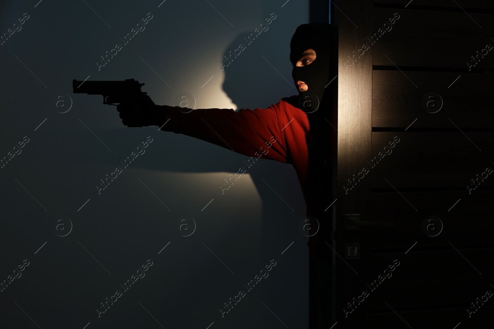 Photo of Thief with gun entering foreign house at night. Burglary