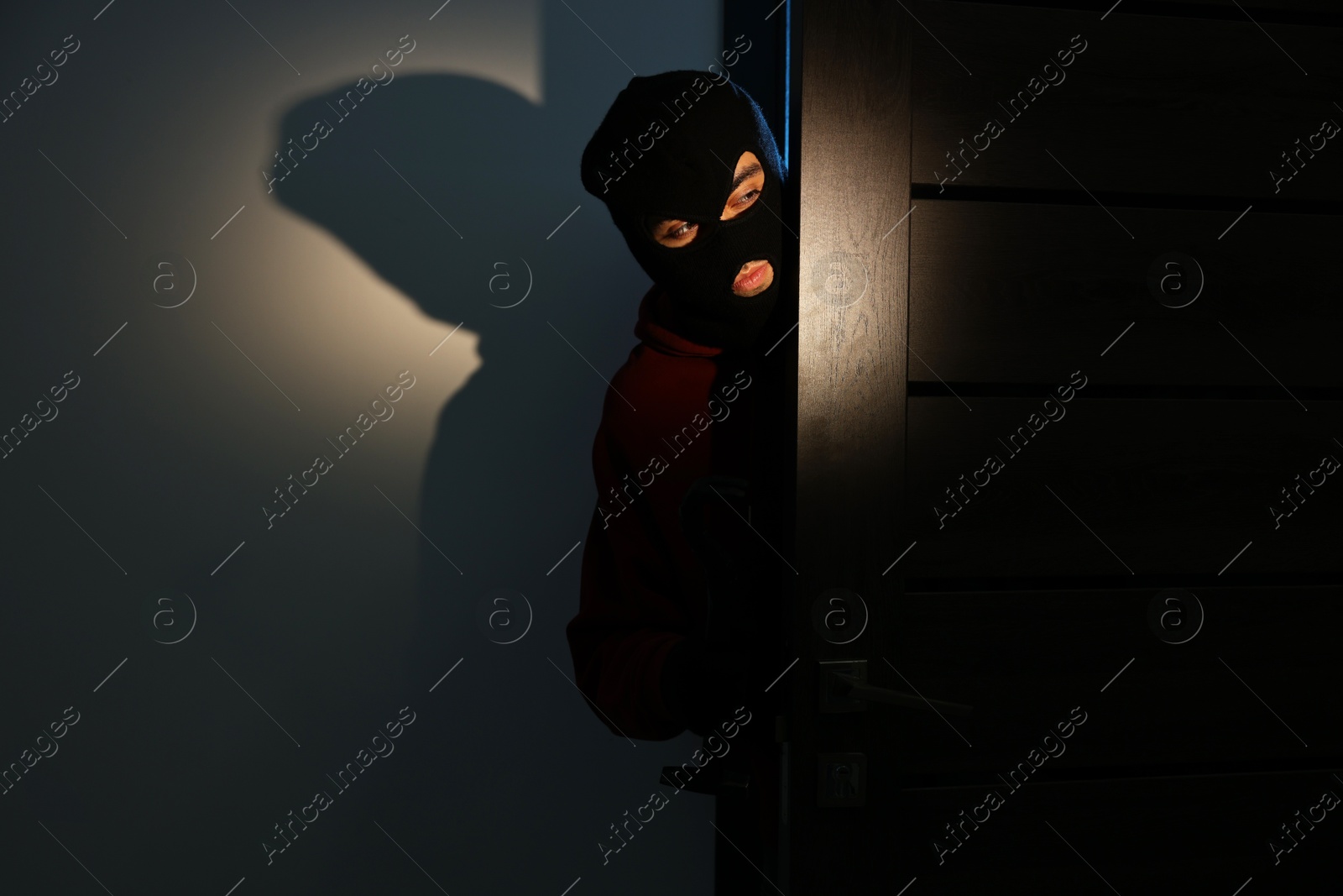 Photo of Thief in balaclava entering foreign house at night, space for text. Burglary