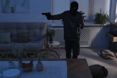 Photo of Thief with gun stealing jewels in foreign house. Burglary