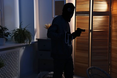 Photo of Thief with gun stealing jewels in foreign house. Burglary