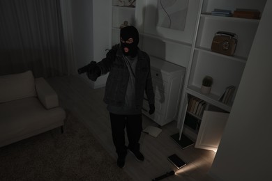 Photo of Thief with gun at foreign house. Burglary