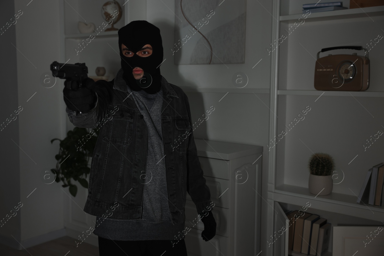 Photo of Thief with gun at foreign house. Burglary