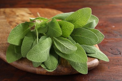 Photo of Green sage leaves on wooden table, closeup