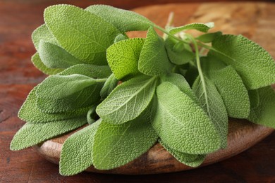 Photo of Green sage leaves on wooden table, closeup