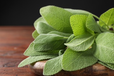 Photo of Green sage leaves on wooden table, closeup