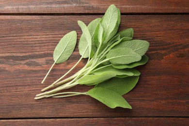 Photo of Green sage leaves on wooden table, top view