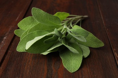 Photo of Green sage leaves on wooden table, closeup