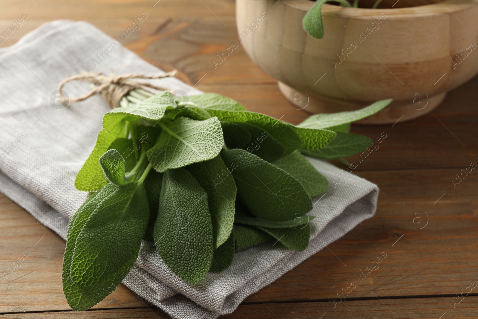 Photo of Bunch of green sage leaves on wooden table, closeup