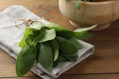 Photo of Bunch of green sage leaves on wooden table, closeup