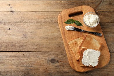 Delicious toasted bread slices with cream cheese, mint and knife on wooden table, top view. Space for text