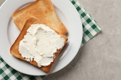 Photo of Delicious toasted bread slices with cream cheese on grey textured table, top view