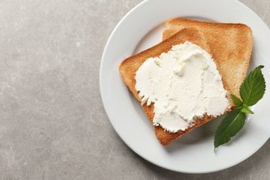 Photo of Delicious toasted bread slices with cream cheese and mint on grey textured table, top view. Space for text