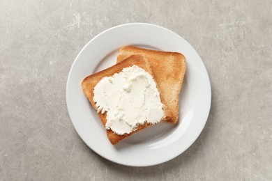 Photo of Delicious toasted bread slices with cream cheese on grey textured table, top view