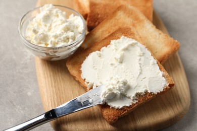 Photo of Delicious toasted bread slices with cream cheese and knife on grey table, closeup