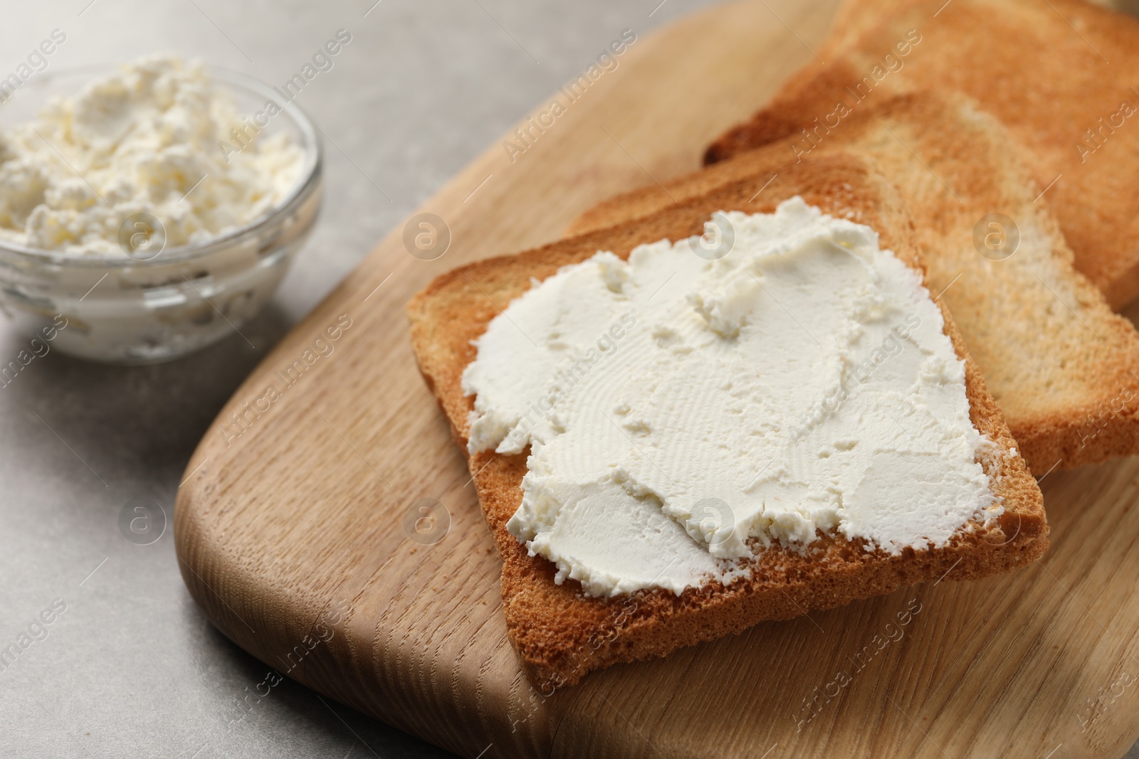 Photo of Delicious toasted bread slices with cream cheese on grey table, closeup