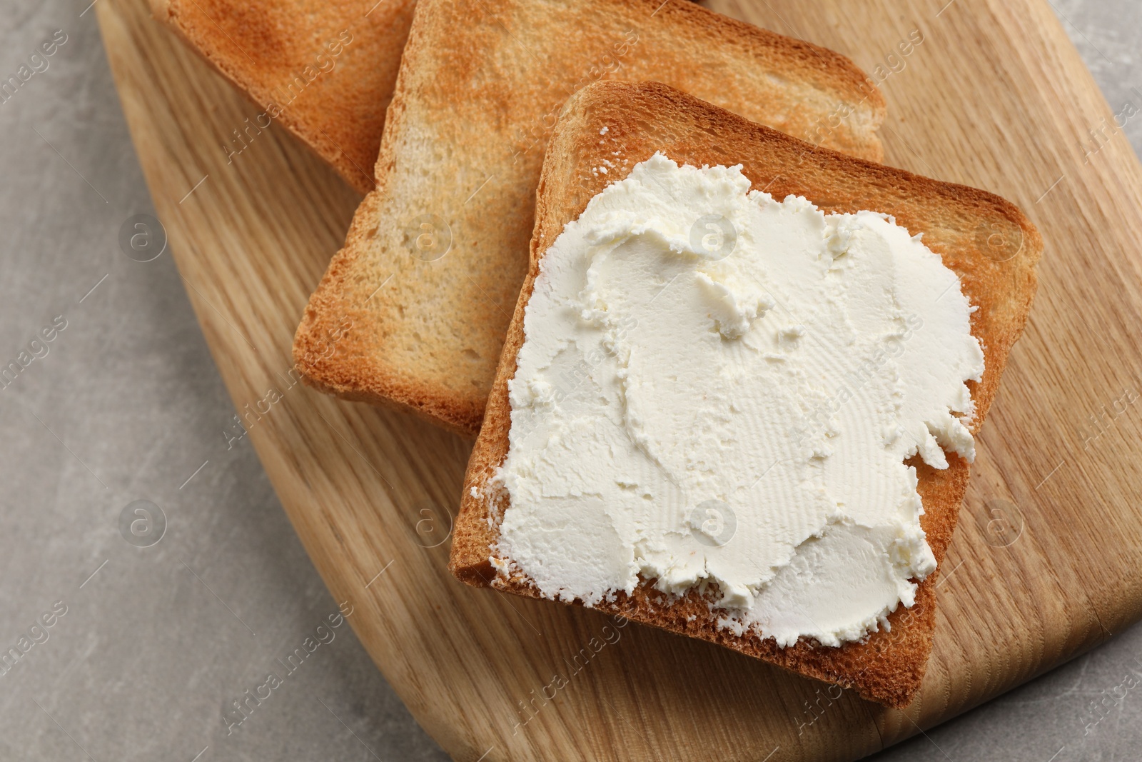 Photo of Delicious toasted bread slices with cream cheese on grey table, closeup