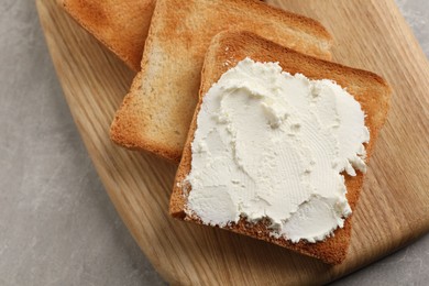 Photo of Delicious toasted bread slices with cream cheese on grey table, closeup