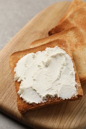 Photo of Delicious toasted bread slices with cream cheese on grey table, closeup