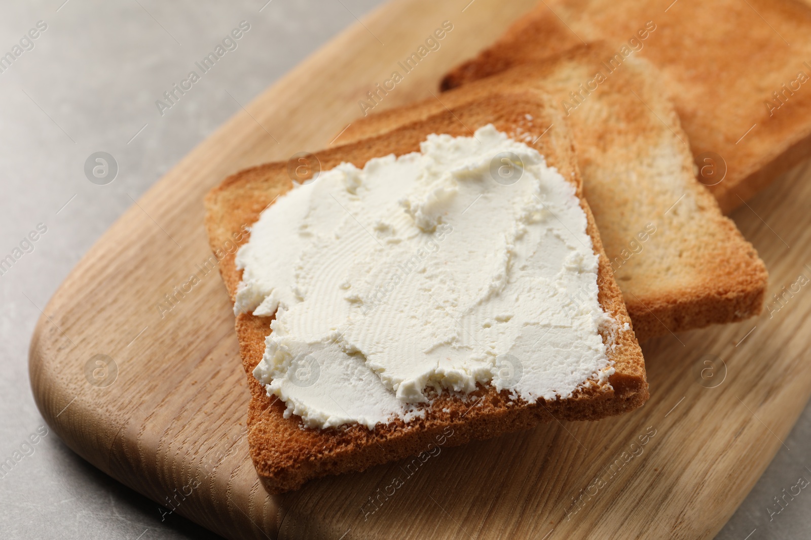 Photo of Delicious toasted bread slices with cream cheese on grey table, closeup