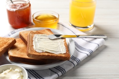 Photo of Delicious toasted bread slices with butter served on white wooden table