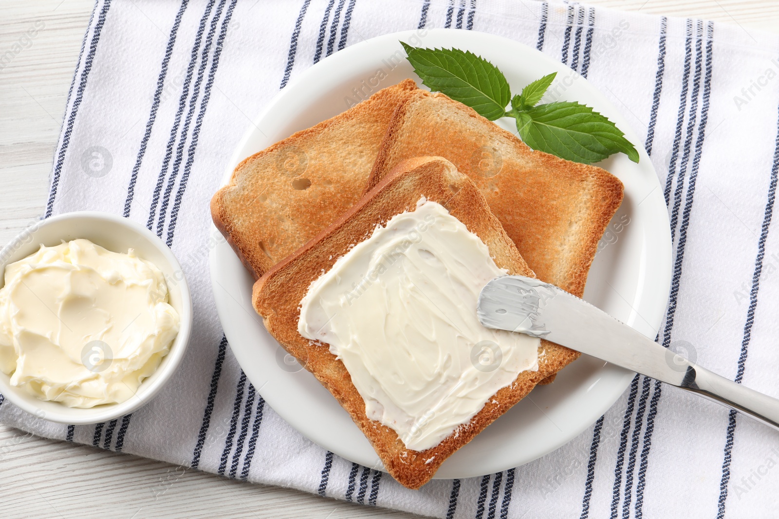 Photo of Delicious toasted bread slices with butter and mint on white wooden table, flat lay