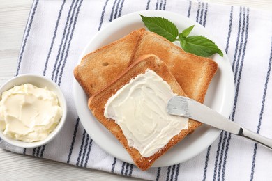 Delicious toasted bread slices with butter and mint on white wooden table, flat lay