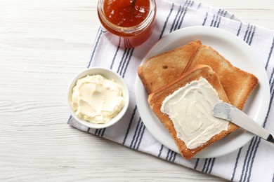 Photo of Delicious toasted bread slices with jam and knife on white wooden table, flat lay