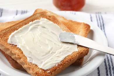 Photo of Delicious toasted bread slices with butter served on table, closeup