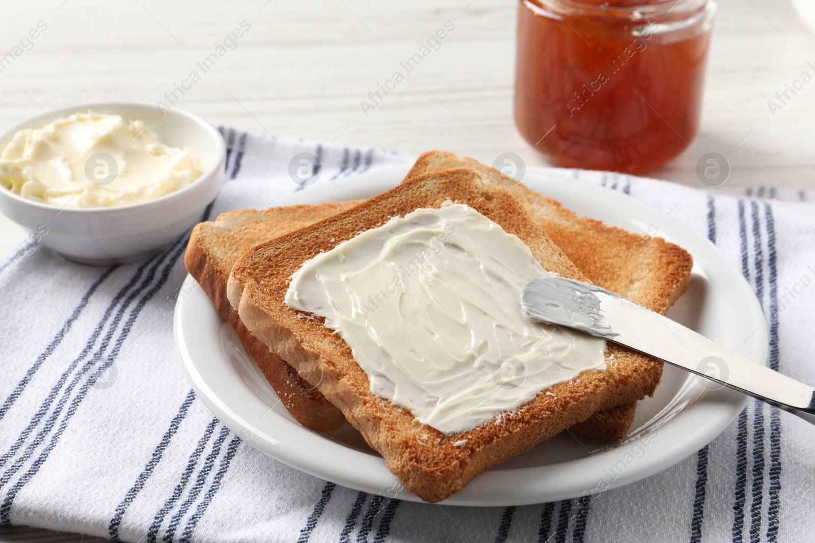 Photo of Delicious toasted bread slices with butter served on white table