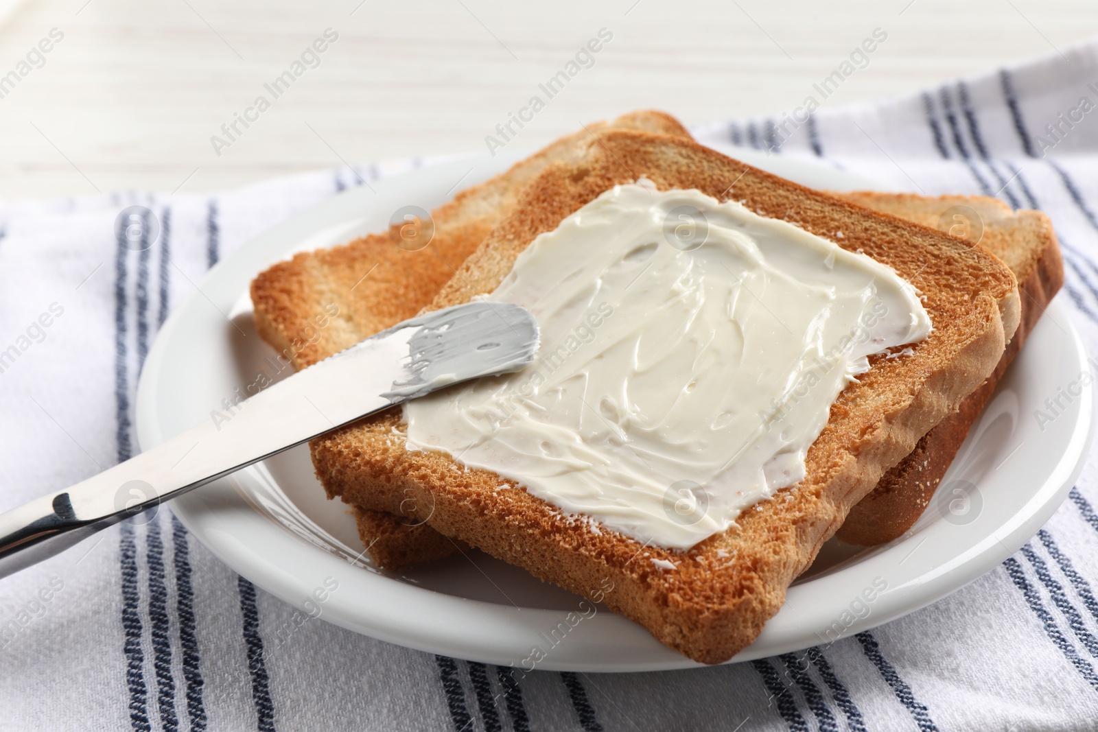 Photo of Delicious toasted bread slices with butter and knife on white table