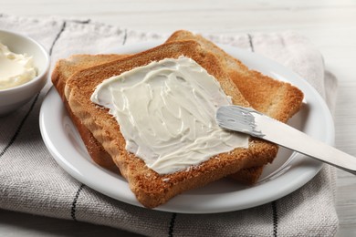 Photo of Delicious toasted bread slices with butter and knife on white table