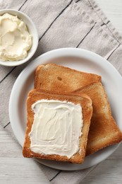 Delicious toasted bread slices with butter on white wooden table, flat lay