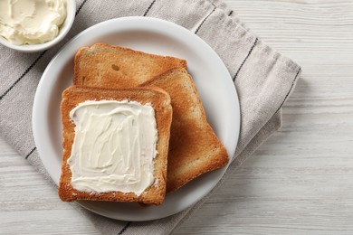 Delicious toasted bread slices with butter on white wooden table, flat lay