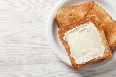 Photo of Delicious toasted bread slices with butter on white wooden table, top view. Space for text