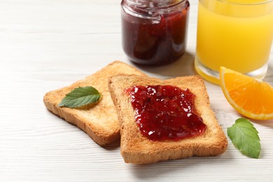 Photo of Delicious toasted bread slices with jam served on white wooden table