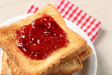 Photo of Delicious toasted bread slices with jam on table, closeup