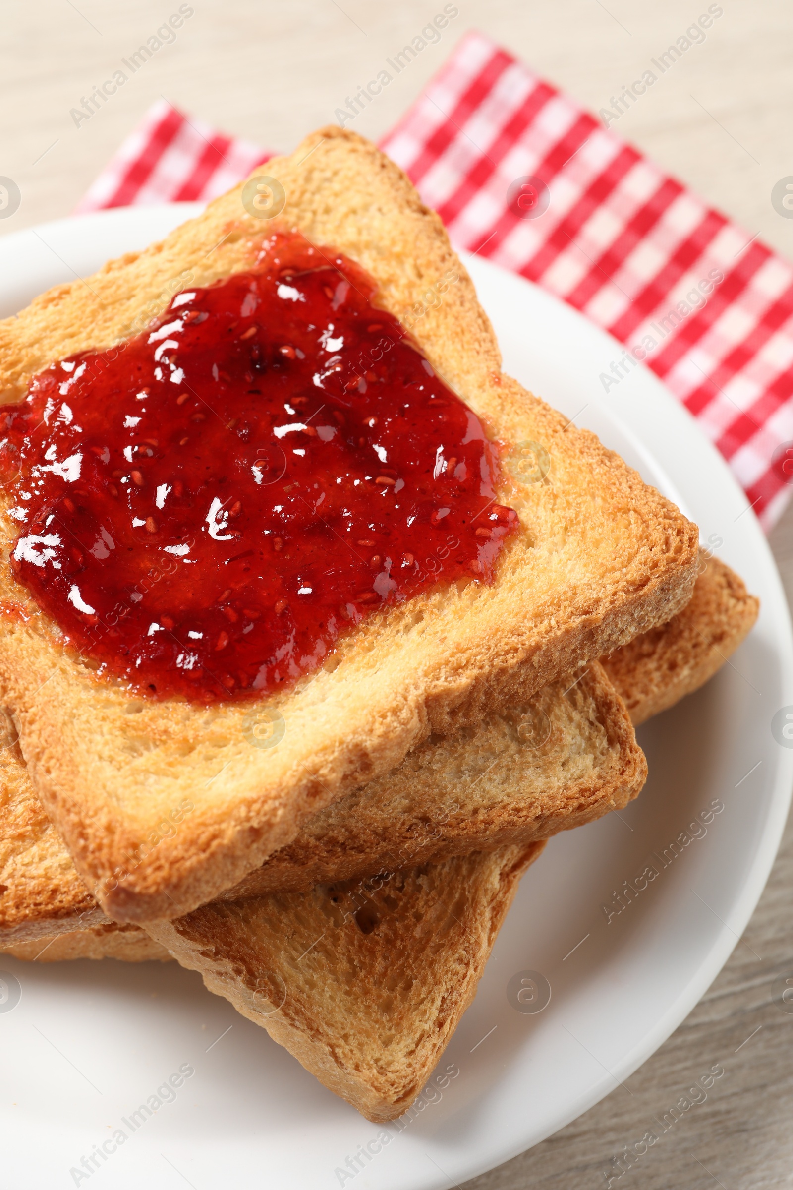 Photo of Delicious toasted bread slices with jam on table, closeup