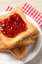 Photo of Delicious toasted bread slices with jam on table, closeup