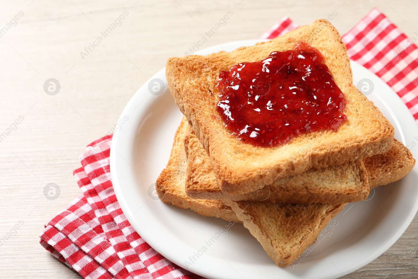 Photo of Delicious toasted bread slices with jam on wooden table