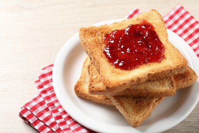 Photo of Delicious toasted bread slices with jam on wooden table