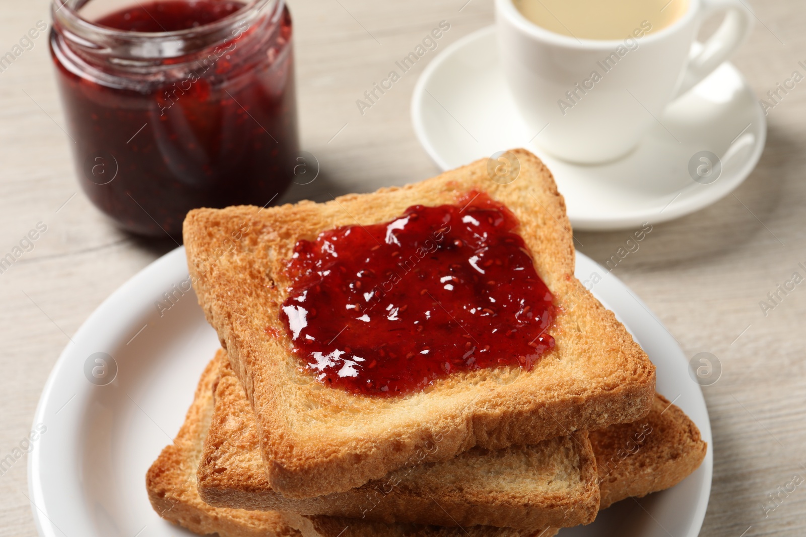 Photo of Delicious toasted bread slices with jam served on wooden table, closeup