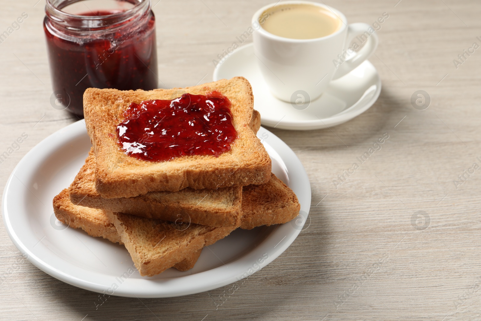 Photo of Delicious toasted bread slices with jam served on wooden table