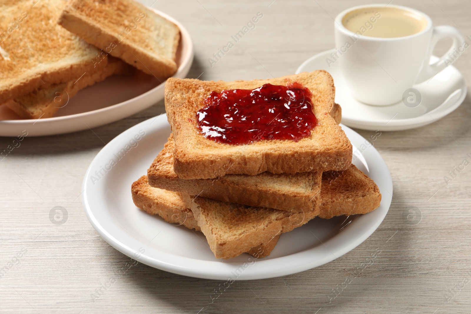 Photo of Delicious toasted bread slices with jam served on wooden table