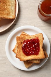 Photo of Delicious toasted bread slices served on wooden table, flat lay