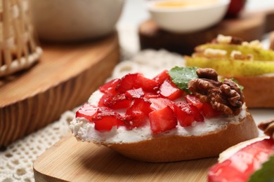 Delicious bruschettas with ricotta cheese, strawberries, walnuts and mint on table, closeup