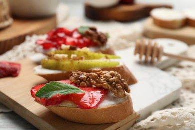 Photo of Delicious bruschettas with ricotta cheese, strawberries, walnuts and mint on table, closeup