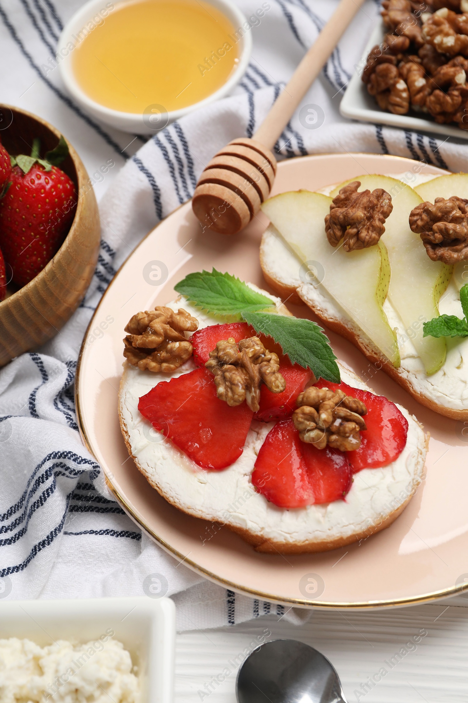 Photo of Plate with different tasty ricotta bruschettas and ingredients on white wooden table, above view