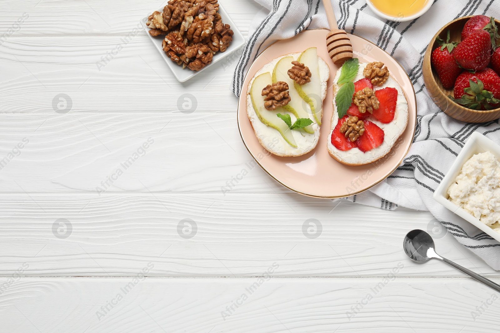 Photo of Plate with different tasty ricotta bruschettas and ingredients on white wooden table, flat lay. Space for text